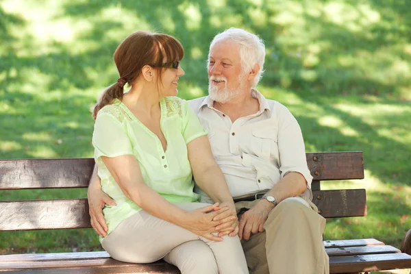 Senior couple sitting on a park bench — Stock Photo, Image