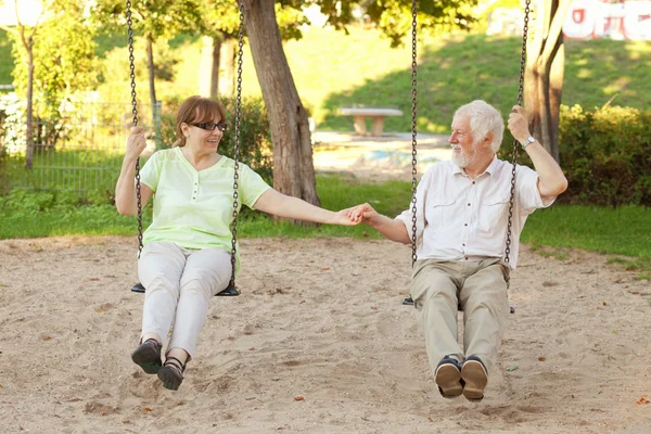 年长的夫妇在公园里摇摆 — 图库照片