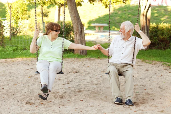 Starší pár, houpání v parku — Stock fotografie