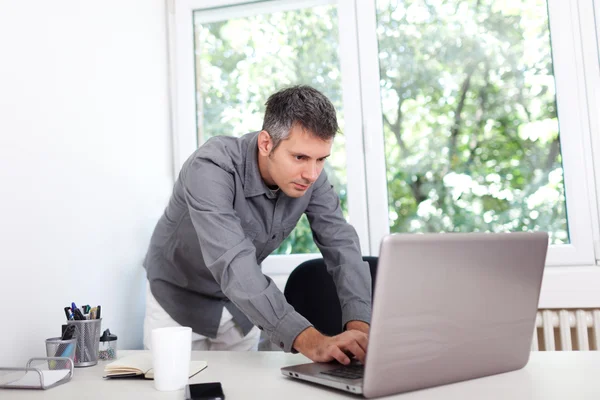 Jeune homme au bureau, travaillant sur ordinateur portable — Photo