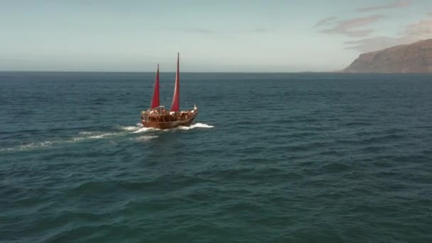 Een oud zeilschip met karmozijnrode zeilen vaart over de oceaan op zoek naar romantisch avontuur — Stockvideo