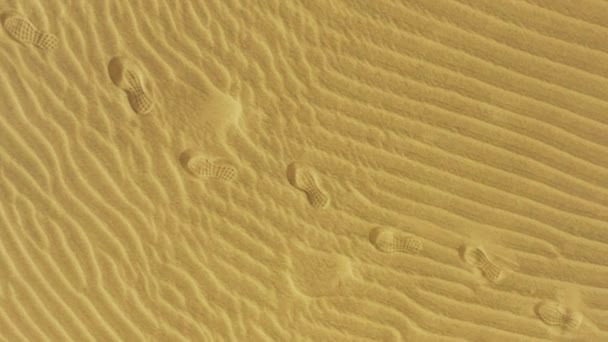 Fußabdrücke auf dem goldenen Sand in der trockenen Wüste — Stockvideo