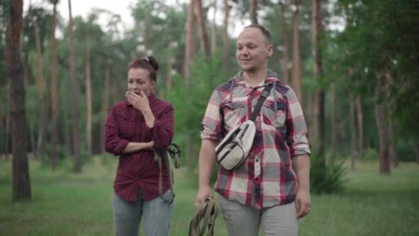 Smiling man and yawning woman walking outdoors with dog leashes. Portrait of Caucasian husband and wife strolling in the morning in summer park or forest. Pet ownership concept. — Stock Video