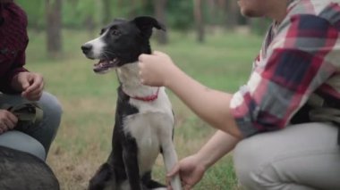 Kafkasyalı özgüvenli bir adam sabah ormanında beyaz ve siyah bir köpeğin pençesini tutuyor. Mutlu bir koca ve ev hayvanı olan tanınmayan bir eş..