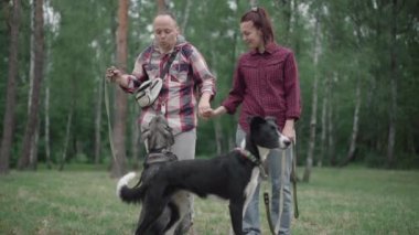 Mutlu adamın köpeklere hayran olduğu ve yaz parkında ya da ormanda kadınları öptüğü geniş bir çekim. Sevgili kocanın portresi. Eşi ve evcil hayvanlarıyla sabah yürüyüşünden keyif alıyor..