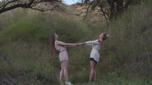 Ampla dose de filha adulta positiva e mãe de mãos dadas e inclinada para trás ao ar livre. Retrato de vista lateral de belas mulheres caucasianas magras em pé no parque de outono. — Vídeo de Stock