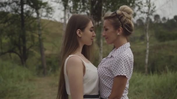 Mittlere Aufnahme von erwachsenen und jungen kaukasischen Frauen, die gemeinsam mit ihren Köpfen im Freien stehen. Porträt der lächelnden, unbeschwerten Damen im Herbstpark an bewölkten Tagen. — Stockvideo
