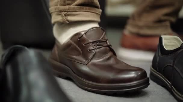 男足与无法辨认的男子近距离接触，试图穿上棕色的靴子。男客户在商店里试穿太小的鞋子。购物和购买. — 图库视频影像