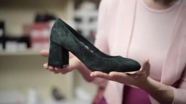 Beyaz kadınların elinde siyah yüksek topuklu ayakkabıların yakın çekimi. Ayakkabıcıdan alışveriş yapan tanınmayan son sınıf öğrencisi. Moda ve tarz kavramı.