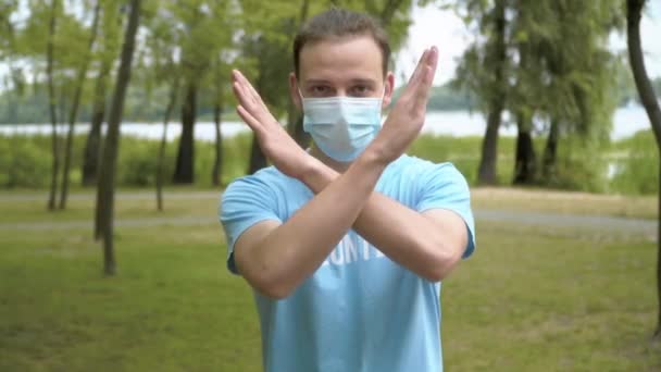 Portrait d'un homme caucasien sérieux ne montrant aucun geste avec les mains croisées. Jeune bénévole au masque facial Covid-19 demandant aux gens d'arrêter la pollution de l'environnement. Écologie et mode de vie mondiaux. — Video