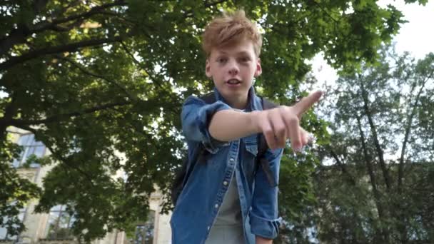 Vista inferiore di aggressiva rossa ragazzo caucasico parlando e indicando la fotocamera. Studente aggressore spaventoso vittima sul cortile della scuola. Concetto di bullismo. — Video Stock