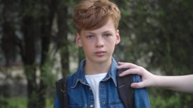 Kızıl saçlı inek öğrenci kameraya tanınamaz sınıf arkadaşları gibi bakıyor ve onu itiyor. Okul bahçesinde tacize uğrayan mutsuz beyaz çocuğun portresi. Zorbalık kavramı.