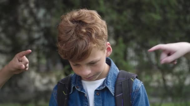 Close-up dari anak sekolah berambut merah dengan teman sekelas dikenali menunjuk wajahnya. Portrait of bullied elementary student suffering of bullying. Agresi dan ancaman. — Stok Video