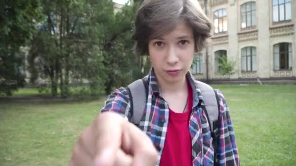 Aggressive brunette schoolboy pointing and talking at camera outdoors. Portrait of cute Caucasian boy with brown eyes threatening victim on schoolyard. Childhood and bullying. — Stock Video