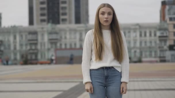 Stressé jeune femme caucasienne debout sur la place de la ville urbaine et regarder autour. Attaque de panique de belle dame mince à l'extérieur en ville. Concept de style de vie stressant. — Video