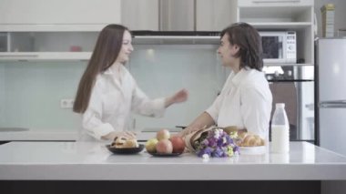 Mutfakta durup konuşan gülen beyaz bir çiftin yan görüntüsü. Güzel genç bir kadının portresi yakışıklı bir adamın saçlarını sarıp gülümsüyor. İlişki ve mutluluk kavramı.