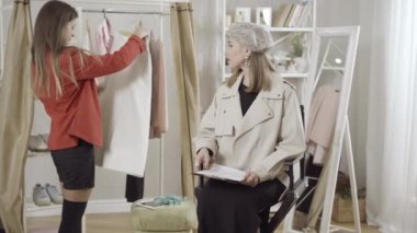 Kendine güvenen profesyonel moda tasarımcıları atölyedeki yeni koleksiyonun eteğini inceliyor. Atölyede tasarım ve trendleri tartışan gülümseyen güzel beyaz kadın portresi.