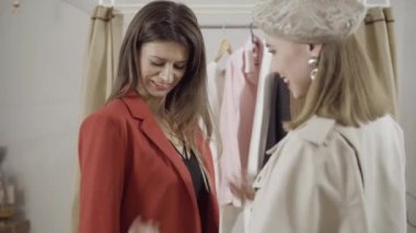 Atölyede ceket deneyen şık bir müşterinin portresi. Moda tasarımcısı ya da terzi mutlu müşterilerin kıyafetlerini kontrol ediyor. Gülümseyen genç beyaz kadın içeride yeni koleksiyonu tartışıyor..