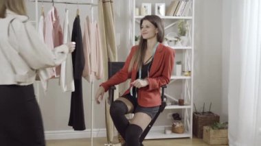 Atölyede kendine güvenen genç bir kadının müşteriyi karşılaması. Güzel gülümseyen beyaz moda tasarımcısının portresi kendine güvenen moda müşterisinin elini sıkıyor ve konuşuyor. İş ve tarz kavramı