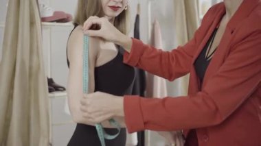 Atölyedeki kol dış dikişlerinin ölçümü. Tanımlanamayan terzi içeride ince ve zarif bir müşterinin kollarını ölçüyor. Bespoke moda konsepti.