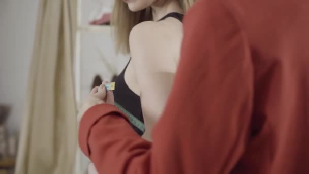 Nierozpoznawalna kobieta mierząca obwód ramienia klienta w pracowni. Profesjonalny młody projektant robi pomiary na indywidualne ubrania. Koncepcja mody i designu. — Wideo stockowe