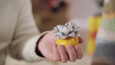 Mandalina tutan, nişan yüzüğüyle tanınmayan bir adamın yakın çekimi. Beyaz adamın kadına evlenme teklif etmesi ve kadın parmağına takı takması..