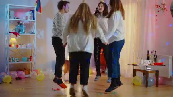 Wide shot of joyful millennial friends jumping in circle and laughing. Happy carefree Caucasian men and women celebrating birthday party indoors at home. Fun and leisure concept. — Stock Video