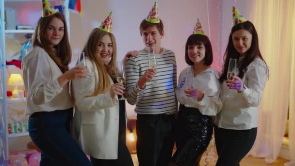 Eine Gruppe fröhlicher Millennial-Männer und -Frauen prostet mit der Kamera zu und trinkt Weißwein aus Gläsern. Positive kaukasische Freunde feiern zu Hause Geburtstagsparty. Millennial Lifestyle. — Stockvideo