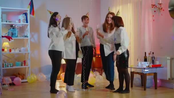 Wide shot of happy millennials toasting, clinking glasses and drinking champagne or white wine on birthday party. Relaxed cheerful Caucasian men and women celebrating partying indoors at home. — Stock Video