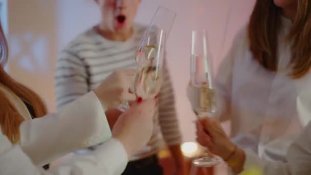 수천 년의 친구들이 실내에서 샴페인이나 화이트 와인 파티를 즐기고 있습니다. 카메라는 생일 파티에서 술과 함께 안경을 따른다. 여가 와 행복의 개념. — 비디오