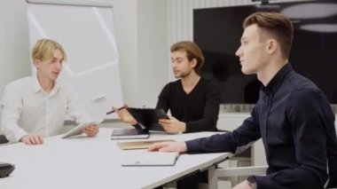 Sıkılmış beyaz bir adamın konferans odasında iş arkadaşlarıyla oturup iç çekerken ve yüzlerine dokunurken yan görüntüsü. Ofisteki aşırı çalışan yorgun çalışanın portresi..