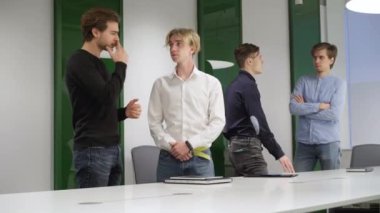 Dört başarılı kendine güvenen meslektaşımız konferans odasında durmuş konuşuyor. Beyaz erkek iş arkadaşları ofiste girişimi tartışıyor. Takım çalışması ve iş birliği.