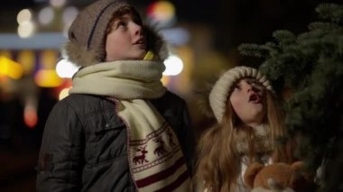 Heyecanlı bir beyaz erkek ve kız dışarı bakıyor ve Noel ışıklarına hayran. Sevimli erkek ve kız kardeş portresi ya da şehirde yeni yılın tadını çıkaran arkadaşlar. Dostluk ve kutlama..