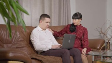 Hamile beyaz kadın kocasının dikkatini dağıtıp laptopta mesajlaşmasını engelliyor. İnternette sörf yapan ya da sosyal medya kullanan, beklenen kadını görmezden gelen dalgın bir adam. Aygıt bağımlılığı ve ilişki sorunları.
