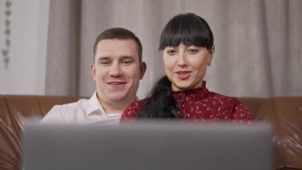 Retrato de homem e mulher caucasiano sorridente olhando para a tela do laptop falando em câmera lenta e dispositivo de fechamento. Feliz casal relaxado assistindo filmes on-line no fim de semana. Conceito de relação. — Vídeo de Stock