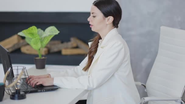 Visão lateral da mulher concentrada trabalhando on-line no laptop com dor nas costas. Exausto estressado caucasiano mulher empregada sofrendo sintomas crônicos de doença sedentária estilo de vida. — Vídeo de Stock