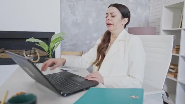 Tânăra femeie obosită căscând și închizând laptopul stând în birou și adormind la masă. Portretul unui angajat caucazian epuizat care doarme la locul de muncă în interior. Conceptul de oboseală . — Videoclip de stoc