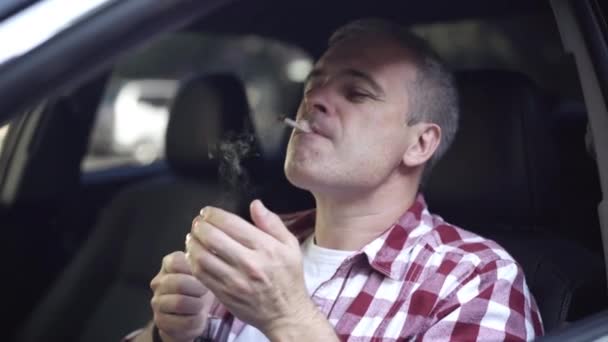 Hombre cigarrillo relámpago y fumar sentado en el coche en el asiento del conductor. Retrato de cerca del estresado hombre de mediana edad del Cáucaso fuma dentro del automóvil. Malos hábitos y estilo de vida poco saludable. — Vídeo de stock