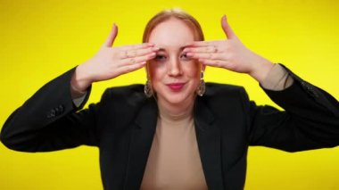 Çilli, kızıl saçlı, zayıf, yeşil gözlü, gözleri kapalı, gülümseyen elleri olan bir kadın. Pozitif özgüvenli beyaz iş kadını portresi sarı arka planda poz verirken eğleniyor.