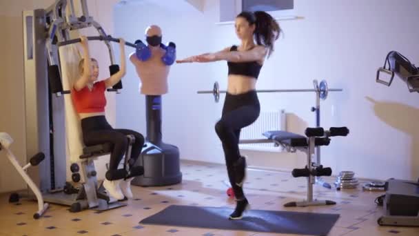 Concentré mince jeune femme en cours d'exécution en place comme belle forme blanche entraînement millénaire à l'aide de la machine d'exercice en arrière-plan. Confiants belles femmes travaillant à l'intérieur dans la salle de gym. — Video