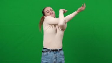 Yeşil ekranda dans eden neşeli, komik kadın gülümsüyor. Chromakey arka planında müzik dansından hoşlanan pozitif, rahat beyaz kadın portresi. Eğlence ve eğlence konsepti.