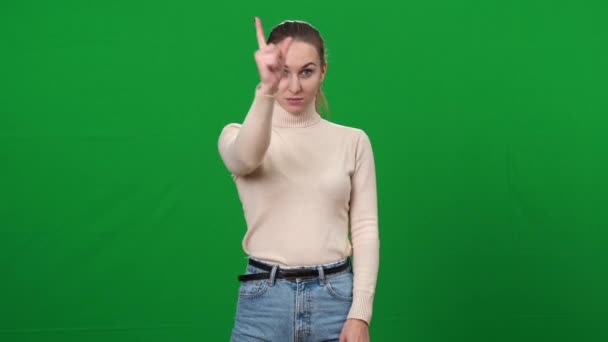 严肃严肃的女人指着站在绿色屏幕上的相机.要求很高的白人女士在铬色背景下看着相机的肖像. — 图库视频影像