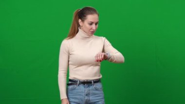 Esmer kadın saati kontrol ediyor ve aceleyle yeşil ekranda koşuyor. Kromakey arka planda acele eden endişeli beyaz kadın portresi.