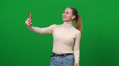 Mutlu kadın yeşil ekranda selfie çekiyor. Kromakey arka planında pozitif beyaz kadın fotoğrafı. Aygıt bağımlılığı ve milenyum yaşam tarzı konsepti.