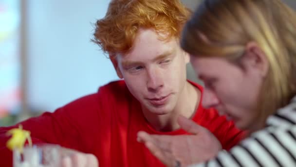 Close-up portret van de jonge roodharige blanke man die zit te praten met een vriend in de bar. Zelfverzekerde, ontspannen vrienden die problemen en geheimen delen in de kroeg. Lifestyle en vriendschap. — Stockvideo