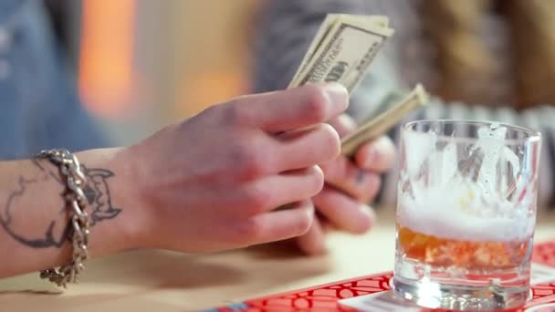 Gros plan des mains masculines comptant l'argent au comptoir de bar au ralenti. Homme caucasien tatoué méconnaissable payant pour des boissons dans un pub. Concept de paiement et de loisirs. — Video