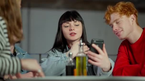 Portrait de jeune femme caucasienne souriante confiante prenant selfie assis avec des amis dans un café ou une pizzeria. Milléniaux détendus parlant reposant à la cafétéria à l'intérieur. Mode de vie et loisirs week-end. — Video