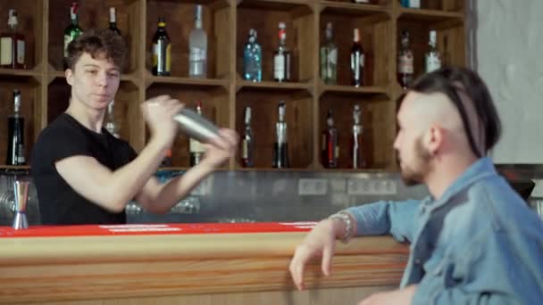 Портрет молодого бармена, який змішує напій для клієнта в барі з коктейлем. Сконцентрований позитивний кавказький бармен, який працює в пабі, готуючи коктейль для розмитого клієнта.. — стокове відео