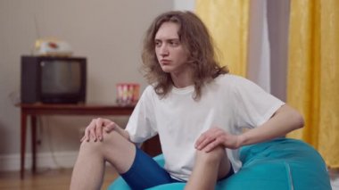 Komik kıvırcık saçlı genç adam yüzünü ekşitmiş kameraya bakıyor. 80 'lerin kapalı mekanlarında eğlenen komik beyaz adamın portresi..