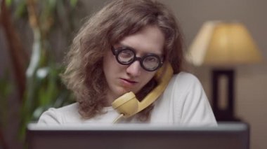 1980 'li yılların akıllı, konsantre bir adamın portresi sarı vintage telefonla konuşan kapalı mekanda retro dizüstü bilgisayarla oturuyor. Dahi Kafkas delikanlısı evinde ya da ofisinde.